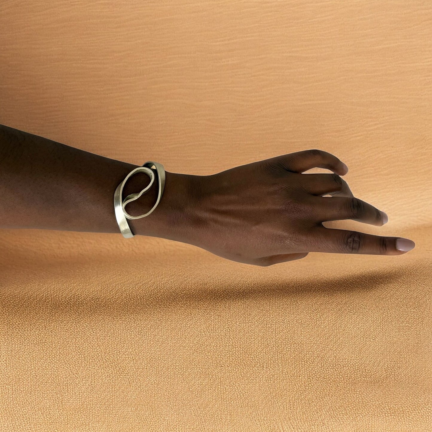 Hand wearing a bracelet on a beige background