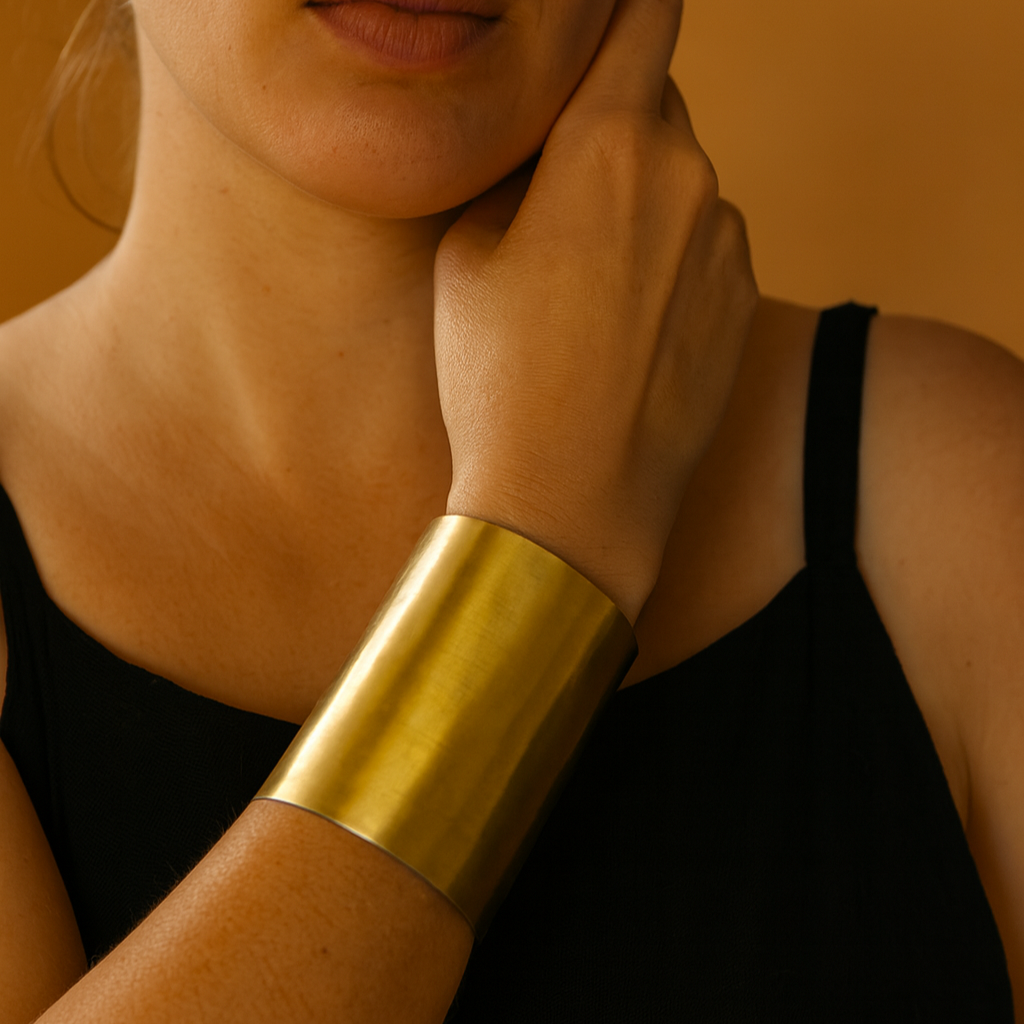 Person wearing a gold arm cuff against a neutral background
