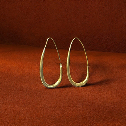 Gold hoop earrings on a rust-colored fabric background