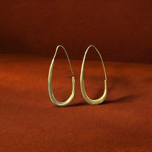 Gold hoop earrings on a rust-colored fabric background